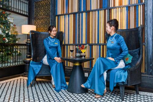 河内Shining Central Hotel & Spa的两名身穿蓝色制服的女性坐在椅子上