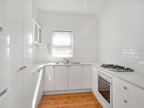 悉尼Stylish & Sunlit Bellevue Hill的白色的厨房设有水槽和炉灶。