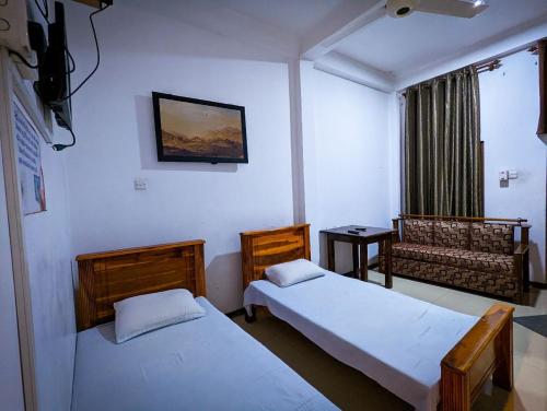 巴杜勒Hotel Change Badulla的客房设有两张床、一张沙发和一个窗口。