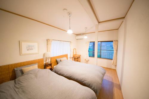 雾岛市おもや彩OmoyaSai-天然温泉付き貸別荘1棟貸し的一间卧室设有两张床和窗户。