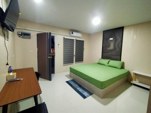 素叻ริมธารริเวอร์เพลส的一间卧室配有一张绿色的床和一张桌子