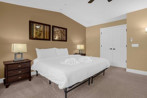 奥兰多4BR. Disney World Vacation Townhome的卧室配有一张白色大床和两盏灯。