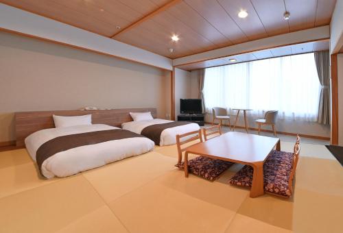 小樽朝里川温泉ホテル的酒店客房设有两张床和一张桌子。