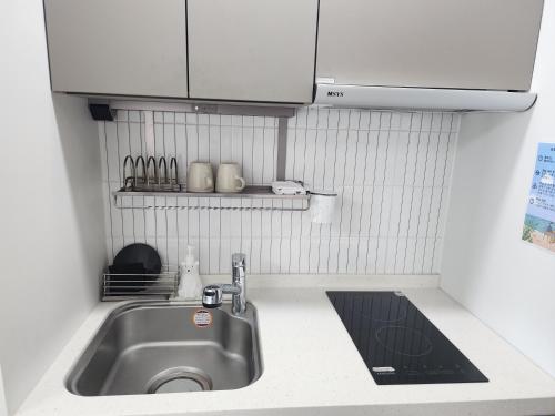 束草市Sokcho Summitbay 1209 "Ocean View"的厨房水槽配有白色橱柜和台面