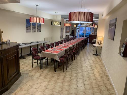 索尔古河畔的恩特莱奎斯Logis Hôtel La Bastide d'Entraigues的长长的用餐室配有长桌子和椅子