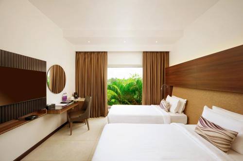 尼杜巴塞莱Flora Airport Hotel and Convention Centre Kochi的酒店客房配有两张床和一张书桌
