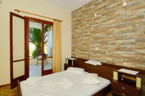 普拉基亚斯Zambia Apartments的一间卧室设有一张床和砖墙