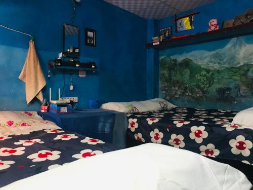 博卡拉Hom's Homestay & campsite Sarangkot Pokhara的蓝色墙壁客房的两张床