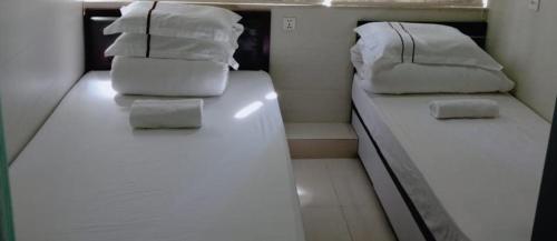 香港金源賓館 Golden Yuan Guest House的小客房内的两张床,配有白色床单和枕头