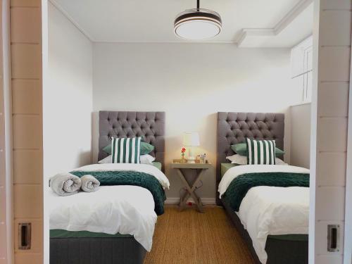 South EndBrizzy's Balcony A Well-located Luxe Retreat的一间卧室配有两张带绿色和白色床单的床