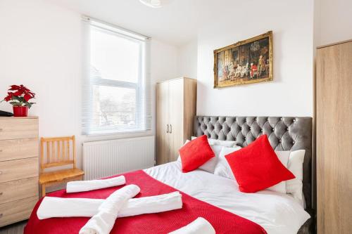伦敦Parkside Stay North London - Victoria Line的卧室配有红色和白色的枕头