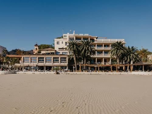 贝尼卡西姆沃拉马尔酒店的海滩上酒店,前方有棕榈树