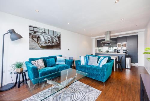 伦敦Austin David Apartments ExCeL的一间带2张蓝色沙发的客厅和一间厨房