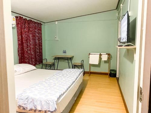 甲米镇Baan Panmala Guesthouse - Ao Luek的一间卧室配有一张床、一台电视和一张桌子