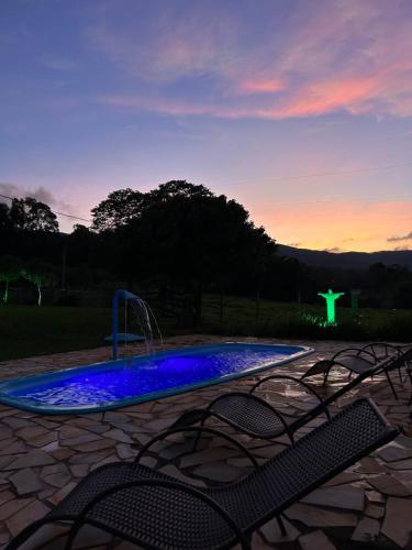 卡皮托利乌Pousada Império de Minas的日落时分带喷泉和椅子的游泳池