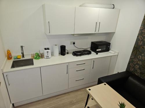 伦敦London Glamour Apartments的小厨房配有白色橱柜和微波炉