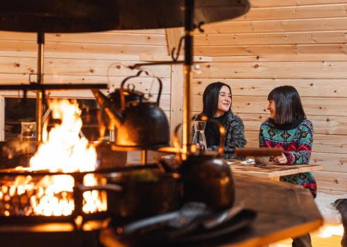 罗瓦涅米Nova Galaxy Village的两个女人坐在火前的桌子上