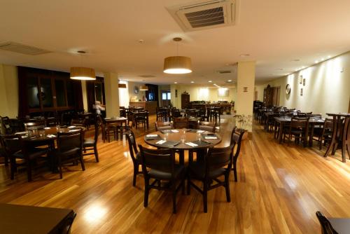 多明戈斯马丁斯Vista Azul Apart Hotel - Vista Pinheiros的餐厅铺有木地板,配有桌椅