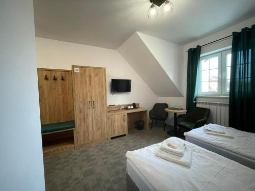 KsiężpolCentrum Turystyki Wiejskiej Alicja的客房设有两张床、一张桌子和一台电视机。