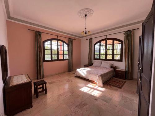 阿加迪尔Tiguimi Vacances - Oasis Villas, cadre naturel et vue montagne的一间卧室设有一张床和两个窗户。
