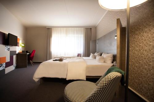 莱比锡Pentahotel Leipzig的配有一张床和一把椅子的酒店客房