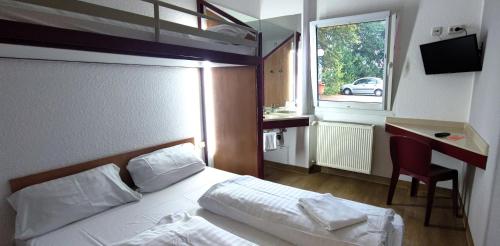 汉诺威汉诺威24小时汽车旅馆的一间卧室配有一张床、一张书桌和一个窗户。