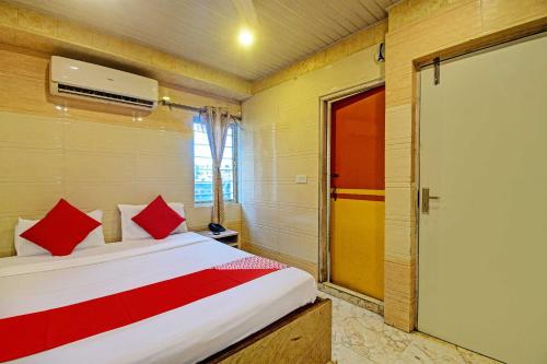 加尔各答Hotel Royal Inn的一间卧室配有一张带红色枕头的床和一扇门