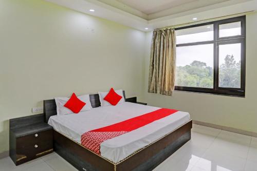 坎普尔OYO Flagship Shree Shyam Kripa Hotel And Restaurant的一间卧室配有一张带红色枕头的床和一扇窗户