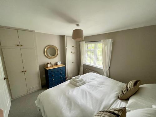 利明顿Seaside Spacious Cosy Cottage On The Edge Of The New Forest的卧室配有白色的床和蓝色梳妆台