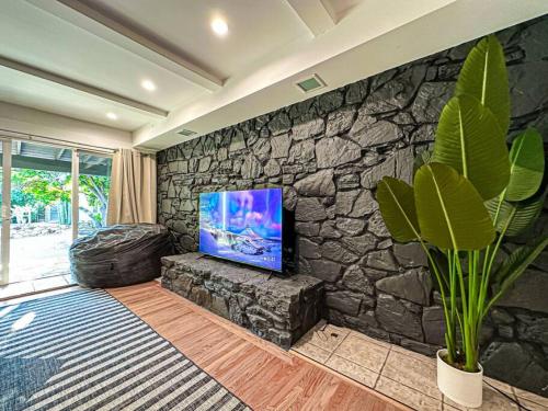 洛杉矶Relaxing 6 BR Oasis with Pool - Lou1的客厅设有石墙和平面电视