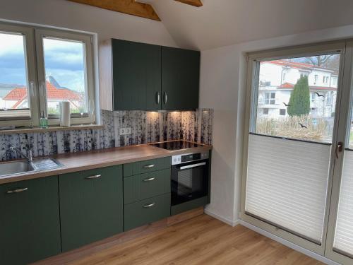 宾茨Altes Fischerhaus in Binz的厨房设有绿色橱柜、窗户和水槽