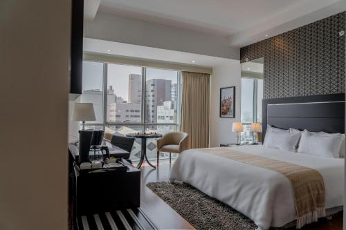 利马何塞·安东尼奥豪华酒店的酒店客房设有一张大床和一张书桌。