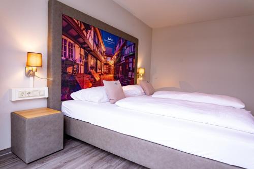 哥根巴赫根根巴赫黑森林酒店的卧室配有一张大床,墙上挂有绘画作品