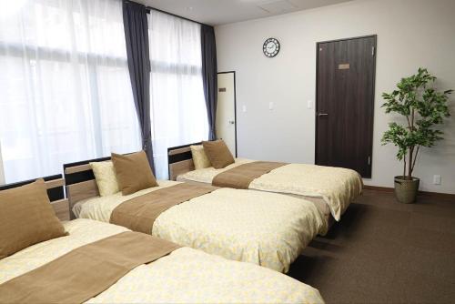 熊本THE TORII - Vacation STAY 21195v的酒店客房设有三张床,墙上挂着一个时钟。