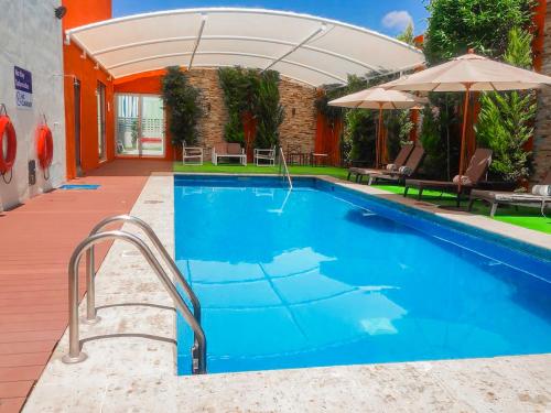 阿瓜斯卡连特斯Hampton Inn & Suites by Hilton Aguascalientes Aeropuerto的一座房子旁带遮阳伞的游泳池