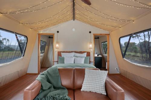 ExcelsiorAkuna Estate - Luxury Glamping Experience的帐篷内一间卧室,配有一张床和一张沙发