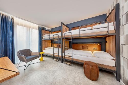 美因茨H2 Hotel Mainz的配有2张双层床的客房配有书桌和椅子。