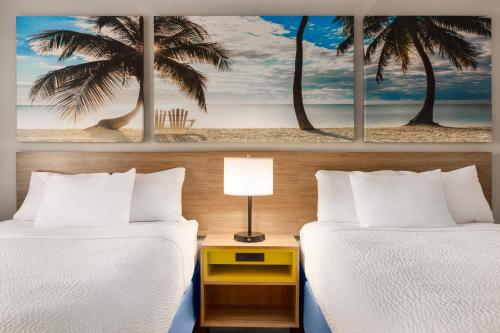 迈阿密迈阿密/机场北戴斯酒店的两张床位于带两棵棕榈树的酒店客房