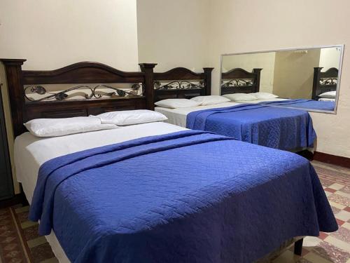 危地马拉Hotel Letona的一间设有三张床、蓝色的盖子和镜子的房间