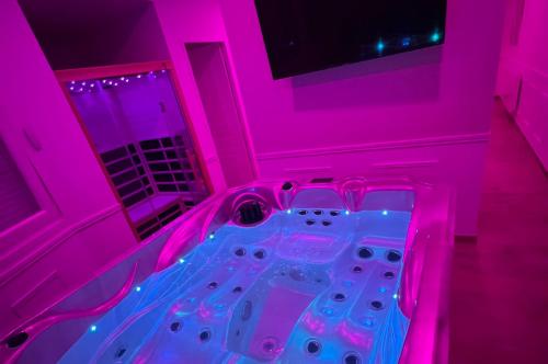 鲁昂Eaux Spa的粉红色的房间,内设热水浴缸