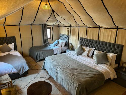 AdrouineNomads Luxury Camp Merzouga的一间帐篷内带两张床的卧室