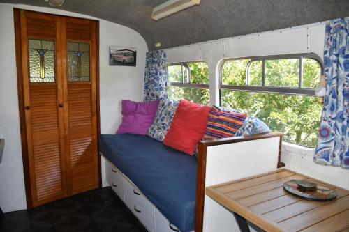 PuketonaEvi the school bus at Oromahoe Downs Farm的小房间设有一张床和一张桌子
