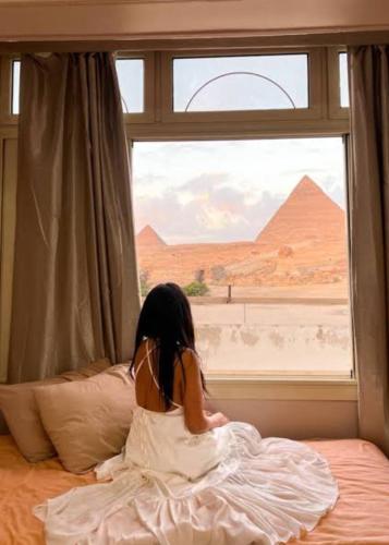 GhaţāţīRoyal pyramids residential的坐在床上,从窗户望出去的小女孩