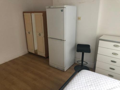 CoseleyComfort zone accommodation near care home的卧室配有白色冰箱和椅子