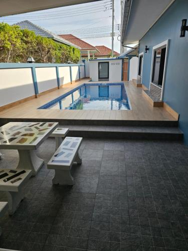七岩Pool Villa Baan Sanook Cha-am的一个带2个长凳和桌子的游泳池