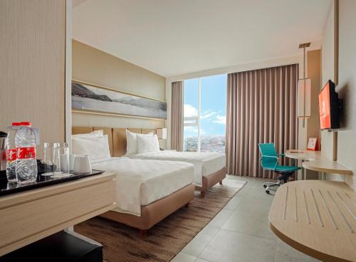 占碑市占碑瑞士贝尔酒店的酒店客房设有一张大床、一张书桌和一张书桌。