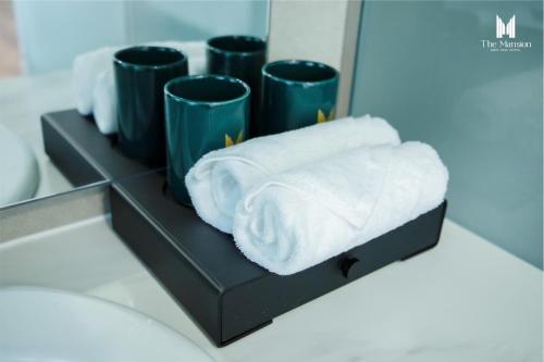 边和The Mansion Hotel Bien Hoa的浴室内带毛巾和杯子的书架