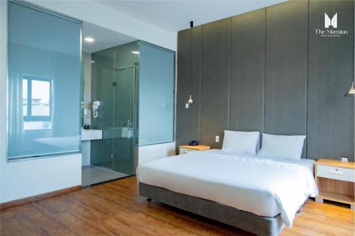 边和The Mansion Hotel Bien Hoa的一间卧室设有一张大床和玻璃淋浴间