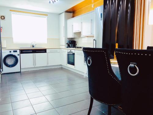 曼彻斯特Manchester City home with parking的厨房配有白色橱柜和黑色椅子