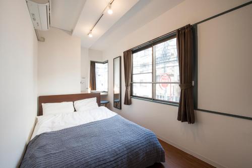 东京KandO Hostel Ueno的一间卧室设有一张床和一个窗口